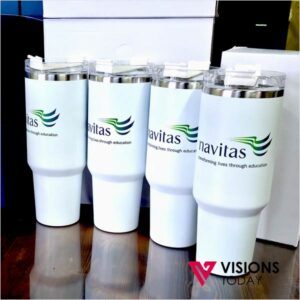 Four white insulated tumblers with the Navitas logo lined up on a wooden surface, the Visions Today watermark at the bottom right.